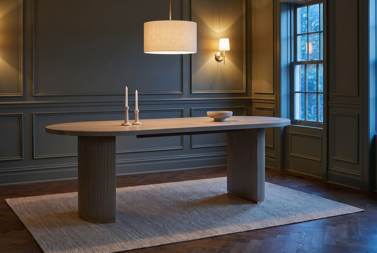 Bobbio dining table in a panelled Toronto dining room at dusk with a linen pendant, a brass sconce and two candlesticks