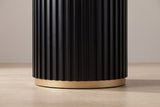 Close-up of the black fluted drum ending just above a plain gold-toned metal ring on a pale oak floor