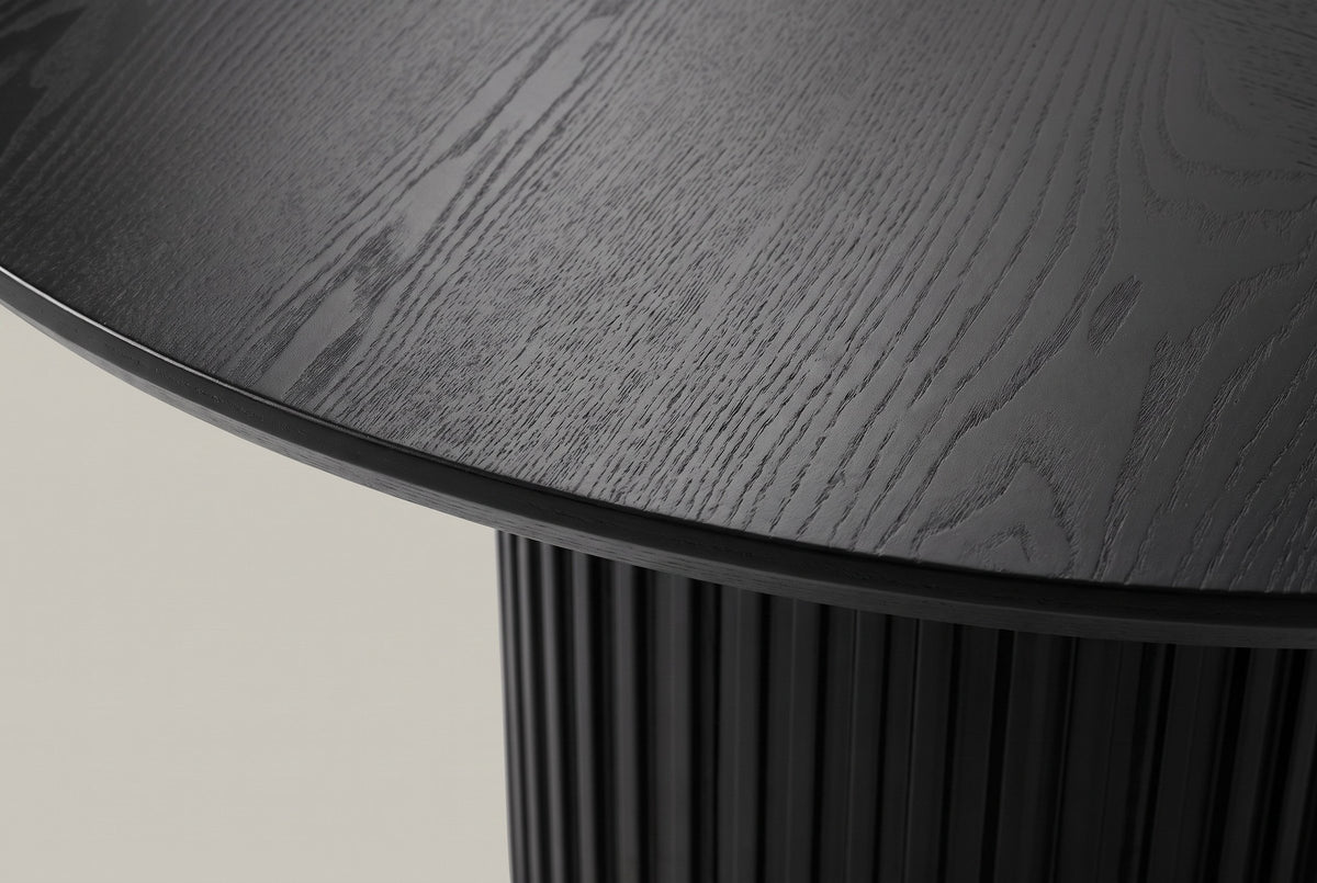 Close-up of the black-stained ash veneer top, its thin edge and the top of the fluted drum below
