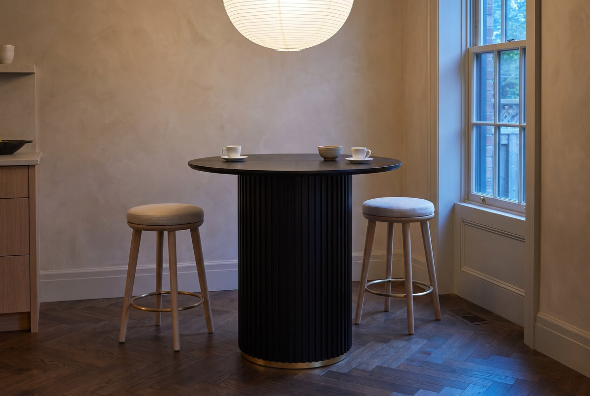 Bolzano table in a Toronto townhouse kitchen at dusk, a paper pendant glowing above and two counter stools beside it