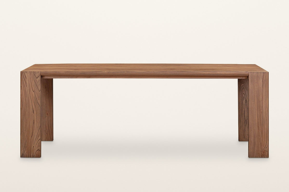Bominaco dining table in Brown, straight front view on a warm white studio backdrop: the long top flush with two wide slab le