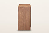The end of the Bominaco sideboard in Brown on a warm white studio backdrop: a thick end panel down to a block foot