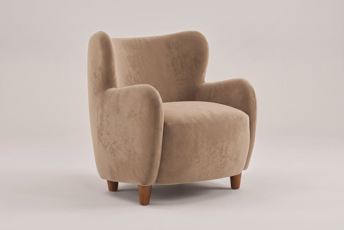 Bormio velvet wingback chair in light camel, three-quarter view on a warm grey studio backdrop