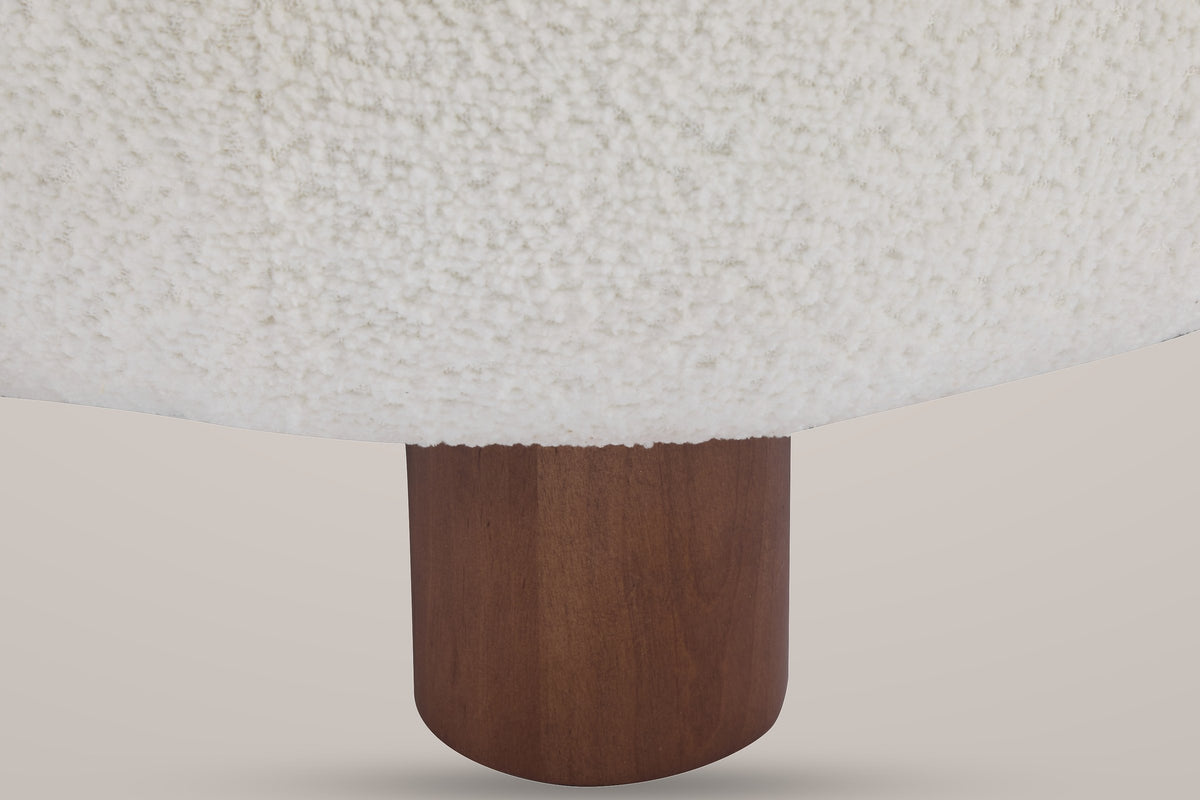 Close-up of a round walnut-finished birch front leg under the curly Off White boucle seat