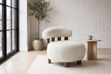 Brescia boucle accent chair in a white-brick loft with a travertine side table