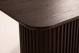 Close-up of the walnut open-grain top: a softly rounded corner, a slim edge and the fluted pedestal below