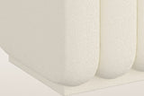 Brusson ottoman close-up: the rounded ends of the channels over the low boucle-covered plinth