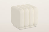 Brusson channel boucle cube ottoman in cream, four rounded channels on a low recessed plinth, three-quarter view on a warm white studio backdrop