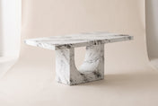 Bryce concrete dining table in a white marble-look finish, three-quarter view on a warm off-white studio backdrop