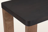 Close-up of a Calcata top corner: the rounded corner and edge band of the mocha mango veneer over a walnut plank leg