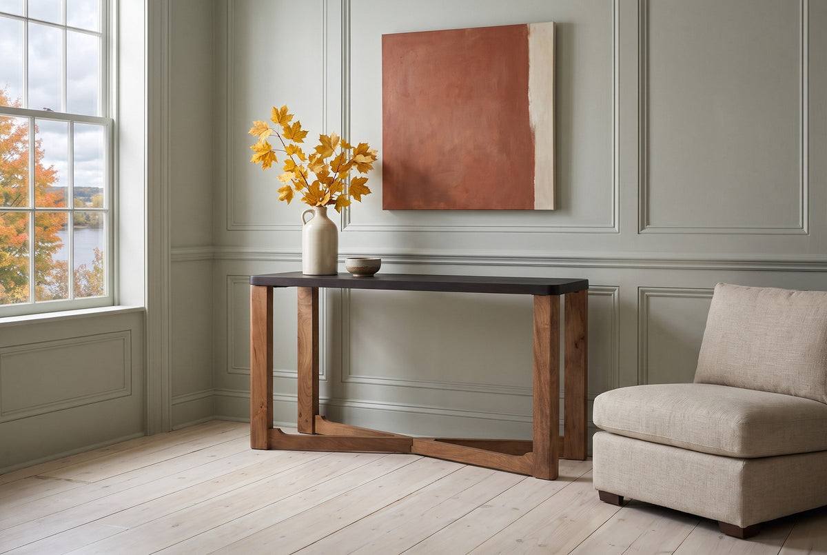 Calcata console table against pale sage panelling in a Fredericton living room, yellow maple leaves in a stoneware jug, an oatmeal linen chair beside it