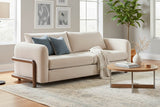 Calista Sand fabric sofa with blue pillows in a bright grey living room