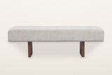 Caltagirone bench in Oatmeal Sand, straight front view on a warm white studio backdrop: the slab legs show only their edges