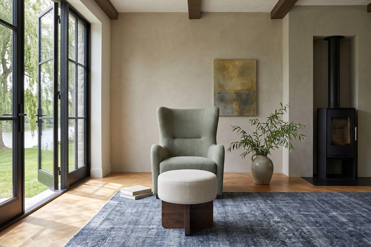Caltagirone stool in Oatmeal Sand facing the camera before a sage wing chair in a Manotick stone house