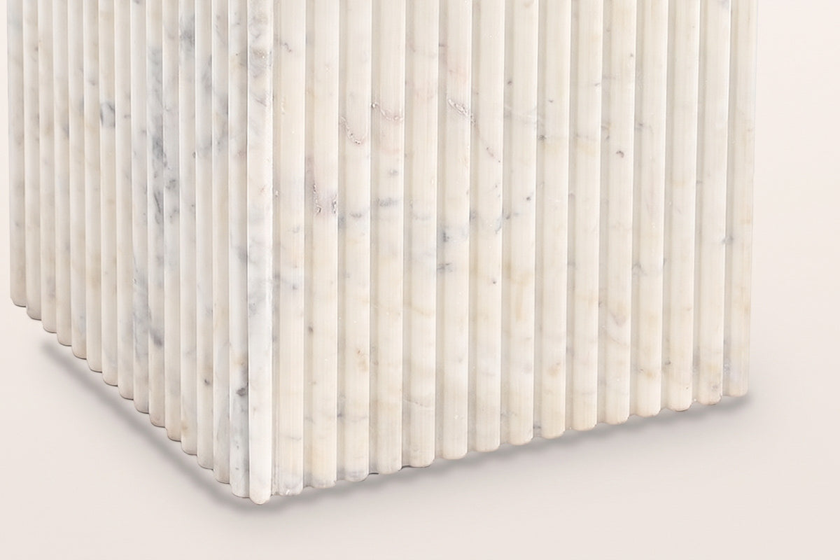 Close-up of the Camerota pedestal corner: narrow marble reeds ending in rounded tips at the floor