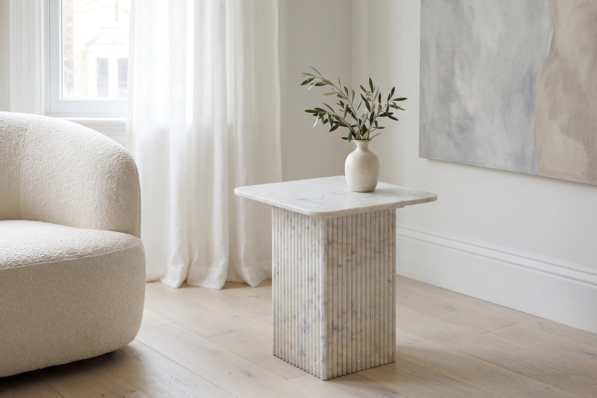 Camerota white marble side table beside a cream boucle armchair in a bright Toronto living room
