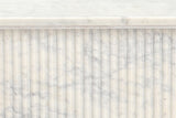 Close-up of the Campiglia pedestal: narrow rounded marble reeds under the edge of the top and its set-back plate