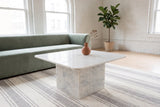 Campiglia white marble coffee table on a striped rug in front of a sage velvet sofa in a white-brick Winnipeg loft with arche