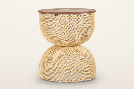 Canale rattan hourglass side table in Natural on a warm white studio backdrop: a round teak top on an open-weave pale rattan