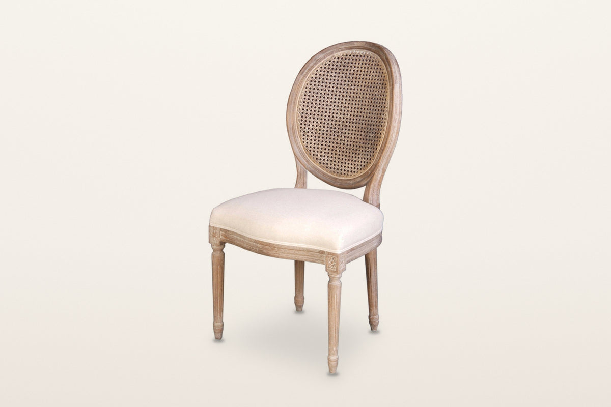 Candelo cane back dining chair, three-quarter view on a warm white studio backdrop: an oval woven cane back in a moulded oak