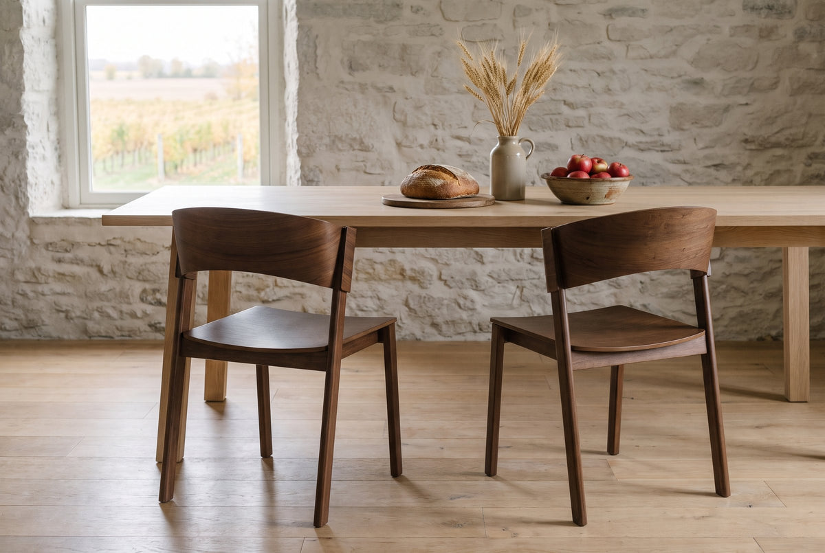 Two Canelli dining chairs in walnut at a long pale oak table in a Prince Edward County farmhouse