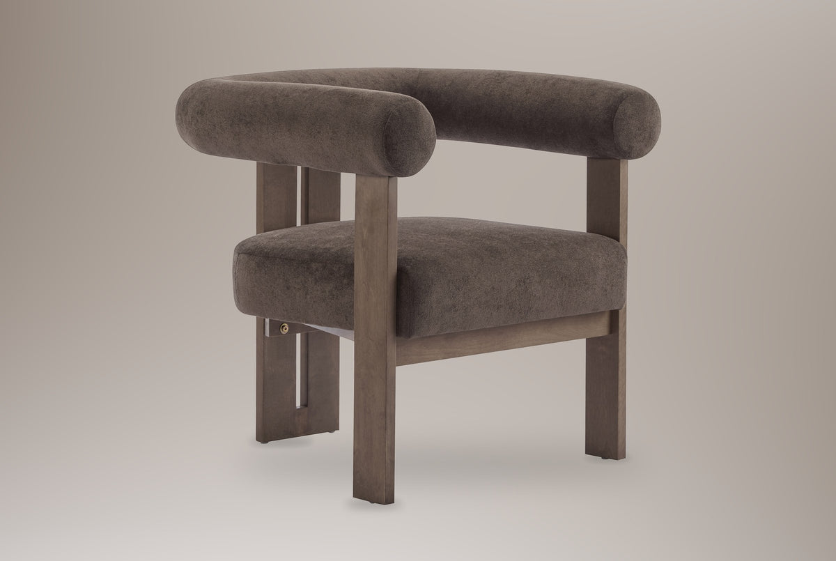 Caorle velvet round-arm accent chair in dark brown, three-quarter view on a warm grey studio backdrop