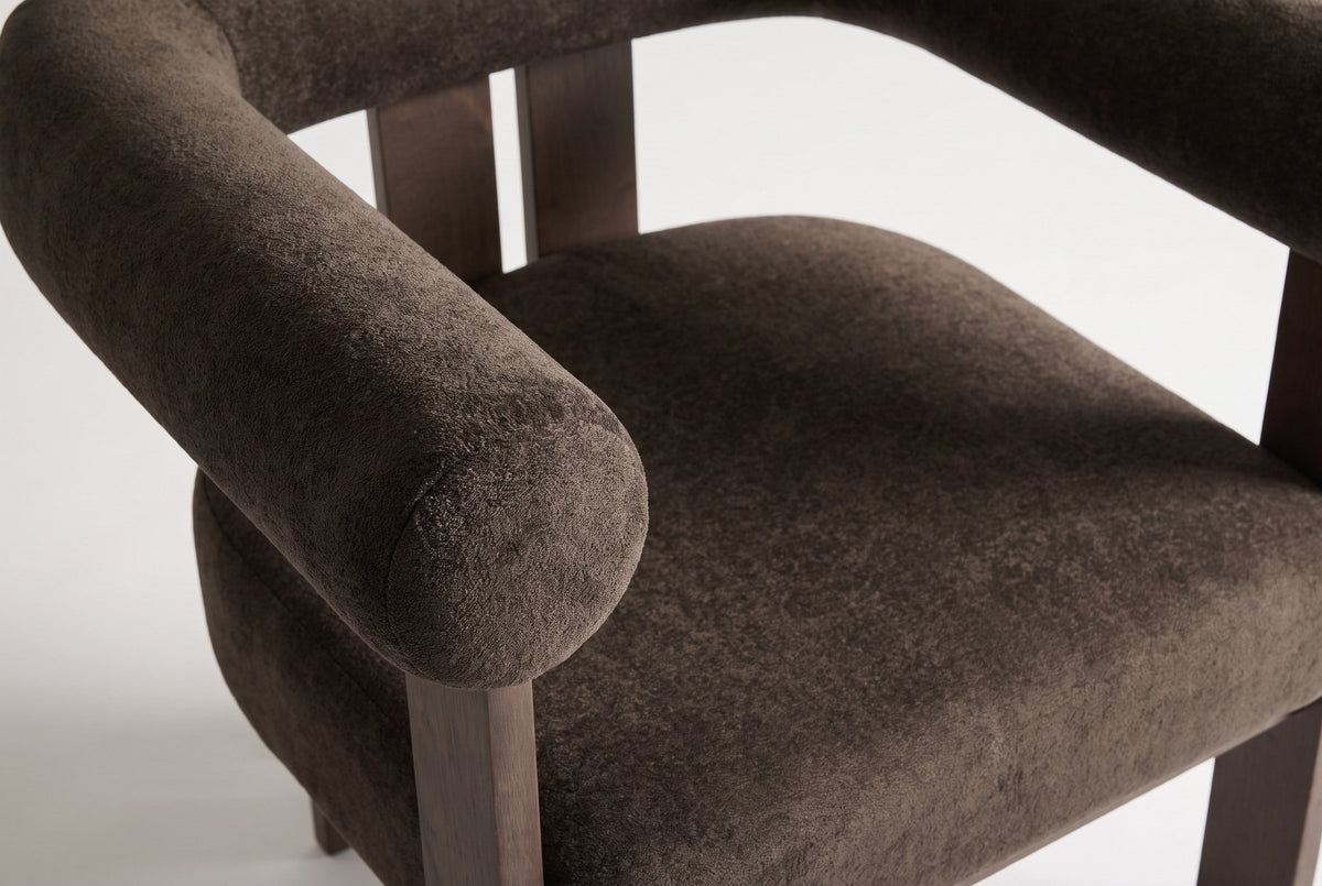 Close-up of the dark brown velvet seat and the flat round end of the arm