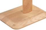 Close-up of the Capalbio base in Natural: the oak post standing on the flat plinth, its chamfered edge and a rounded corner
