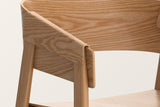 Close-up of the Caprarola arm in natural oak: the bent shell folding over the front leg, open oak grain