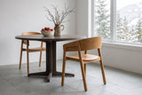 Two Caprarola dining armchairs in natural oak at a round smoked-oak pedestal table in a Whistler mountain home