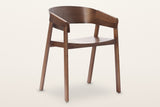 Caprarola dining armchair in walnut, three-quarter view on a warm white studio backdrop