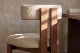Close-up of the wire-brushed oak planks and ivory boucle bolster of the Carlo chair