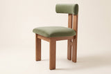 A Carlo oak dining chair with a sage-olive velvet bolster back and seat, side three-quarter view on an off-white background