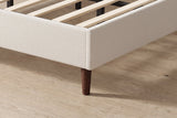 Close-up of the Carrara rail corner in beige chenille on a tapered dark wood leg, with the slats inside