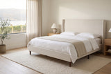 Carrara wingback bed made up with white linen in a bright bedroom with light oak nightstands