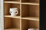 Carver cabinet open shelves in natural wood under the black arched frame