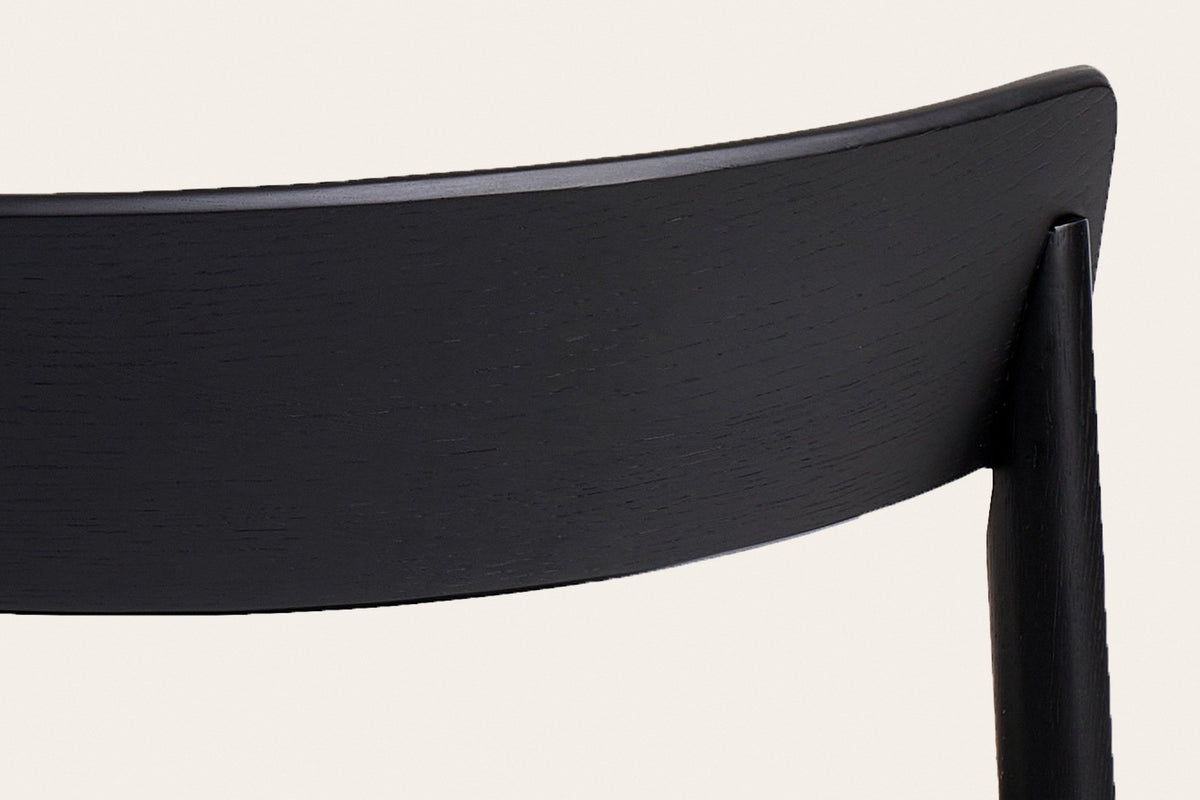 Close-up of the Casole back panel in black-stained oak: the open oak grain under the stain and the post set into the panel