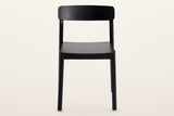 Casole dining chair in black-stained oak, straight front view on a warm white studio backdrop