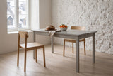 Two Casole dining chairs in natural oak at a grey painted farmhouse table in a Quebec City stone house
