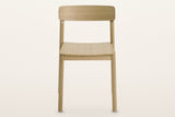 Casole dining chair in natural oak, straight front view: a curved back panel on two round posts over a thin plywood seat