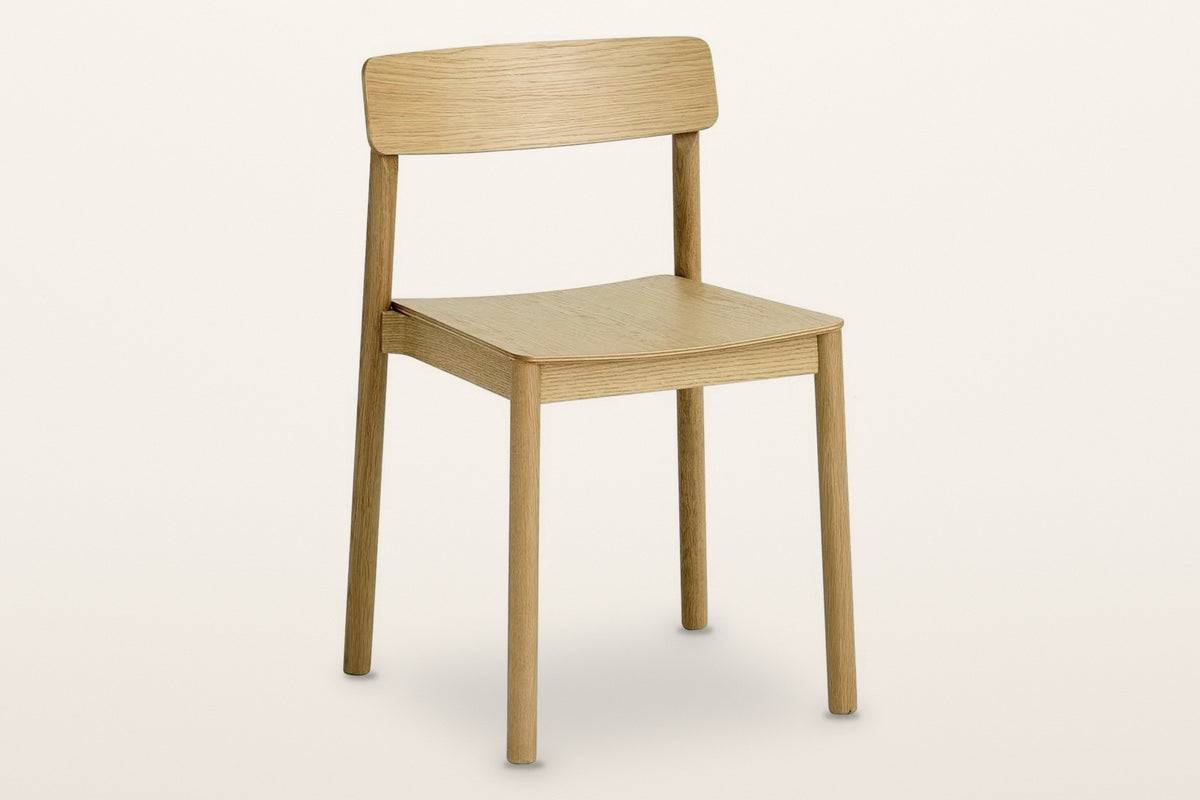 Casole stackable oak dining chair in natural oak, three-quarter view on a warm white studio backdrop