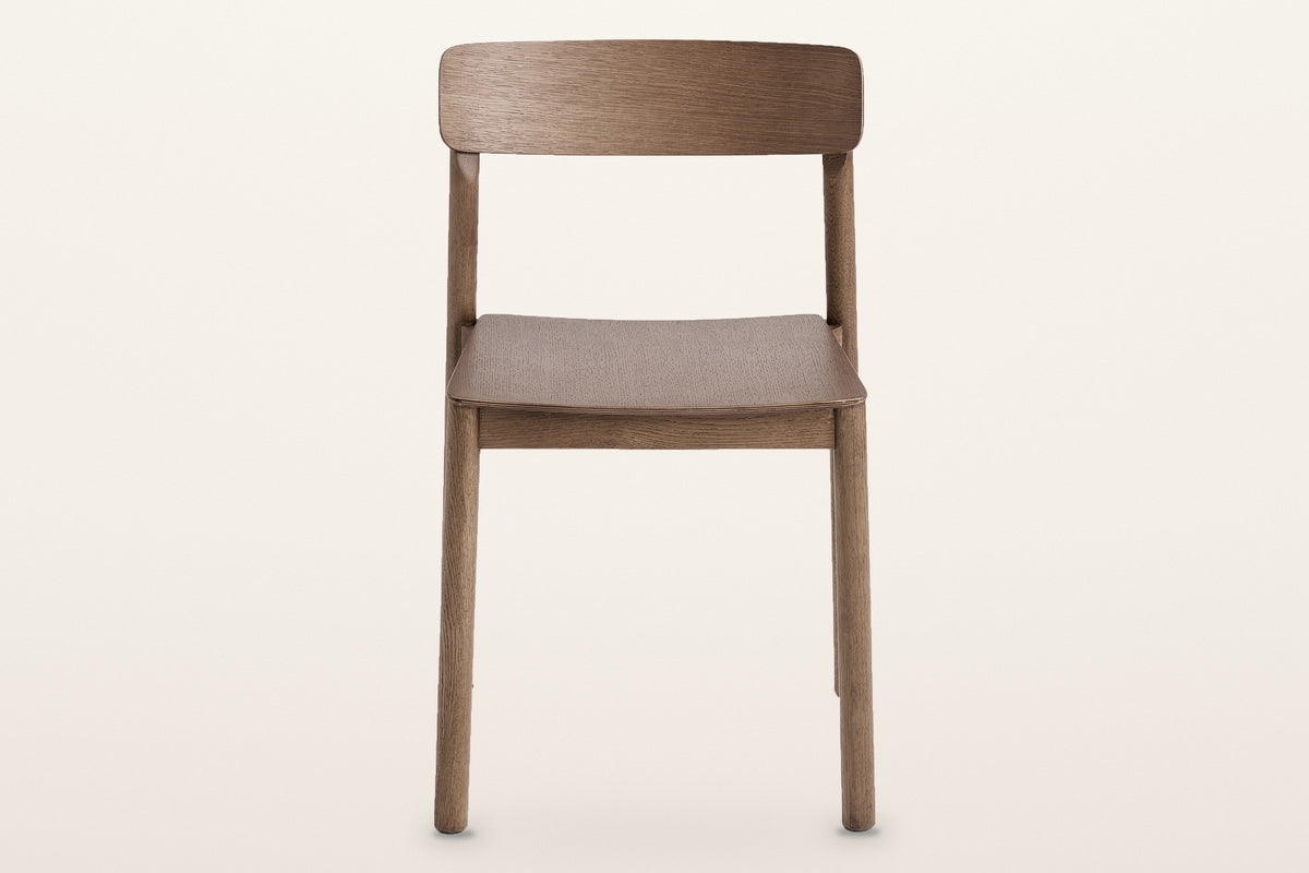 Casole dining chair in walnut-stained oak, straight front view on a warm white studio backdrop