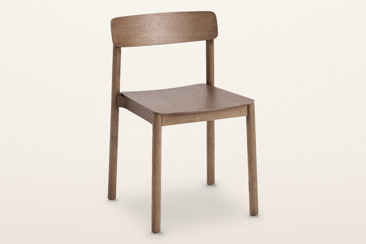 Casole stackable oak dining chair in walnut-stained oak, three-quarter view on a warm white studio backdrop