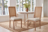 A pair of Castelfranco dining chairs in Beige on a jute rug in a white Muskoka cottage with a round table and the lake behind