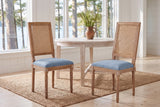 A pair of Castelfranco dining chairs in Denim Blue on a jute rug in a white Muskoka cottage with a round table and the lake b
