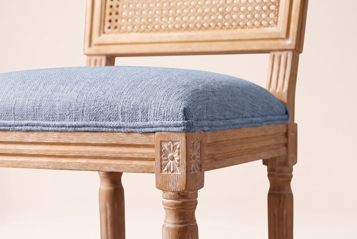 Close-up of the Denim Blue linen-look seat, the reeded rail and the carved rosette on a front corner block