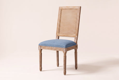 Castelfranco French cane-back dining chair in Denim Blue, three-quarter view on a warm off-white backdrop