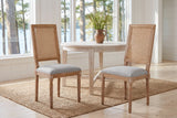 A pair of Castelfranco dining chairs on a jute rug in a white Muskoka cottage with a round table and the lake behind