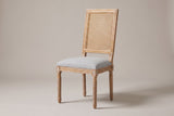 Castelfranco French cane-back dining chair in Light Grey, three-quarter view on a warm light-grey studio backdrop