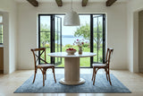 Two Castelmola dining chairs in Brown at a round fluted table in an Ile d'Orleans farmhouse, with white plaster